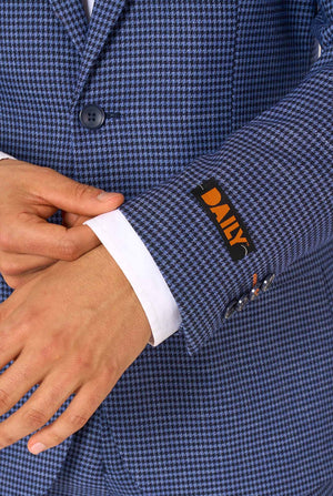 A men wearing a navy and blue checkered suit with a white dress shirt. The suit has a modern fit with two buttons and flap pockets. He stands against a plain white background. Close up of the sleeves