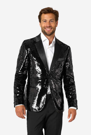 Man wearing a black sequin blazer with a satin shawl collar, paired with a white dress shirt and black trousers, standing and smiling at the camera.