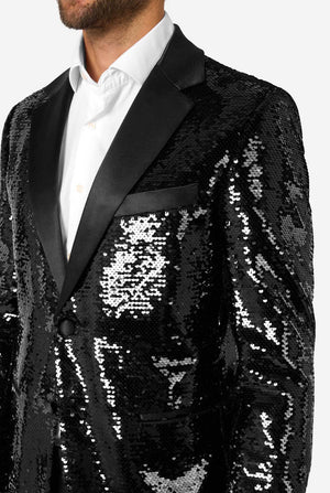 Close-up of upper body in black sequin blazer with satin lapel and pocket trim, paired with a white dress shirt.