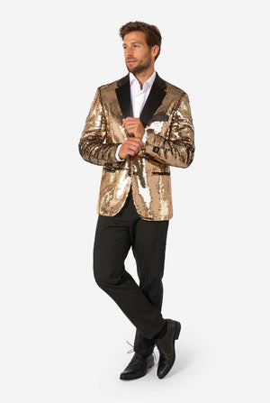 Man dressed in a gold sequin blazer with black lapels, white shirt, and black trousers, posing with arms crossed and one leg slightly bent.