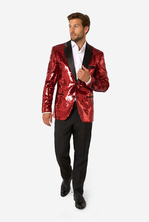 Full-body view of a man in a red sequin blazer with black lapels, white shirt, and black trousers, standing and looking sideways.
