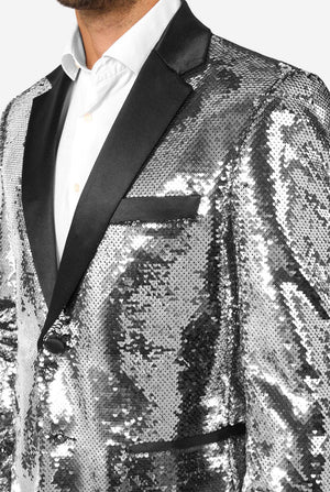 Close-up of the upper part of a silver sequin blazer showing the satin lapel, breast pocket, and shimmering sequin detail.