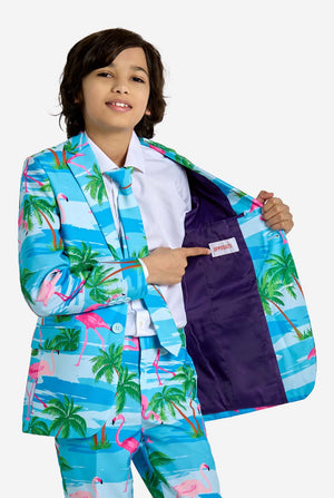 Child wearing a colorful suit with palm tree and flamingo pattern, pointing to the inside pocket.