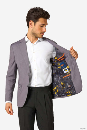 A man in a grey blazer showing the inside lining printed with Batman logos and dark comic patterns.