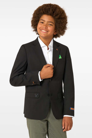 A child smiling while wearing a black blazer, white shirt, and green pocket square.