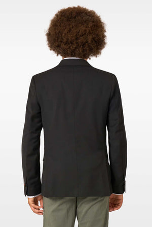 Back view of a child wearing a plain black blazer and olive trousers against a light background.