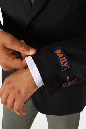 Close-up of a blazer sleeve with an orange label reading “DAILY” above black buttons.