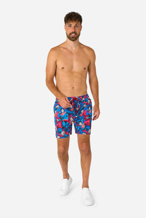 Man wearing a Men's Superman-themed swim shorts featuring a bold comic book design with multiple action poses of the Man of Steel. Perfect for superhero fans looking to make a splash. Full body image.