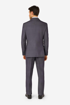 A man is wearing a stylish charcoal colored grey suit with a white dress shirt, looking confidently. Perfect formal outfit for men's special occasions, weddings, and parties. View from the back.