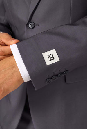A man is wearing a stylish charcoal colored grey suit with a white dress shirt, looking confidently. Perfect formal outfit for men's special occasions, weddings, and parties. Sleeve close up.