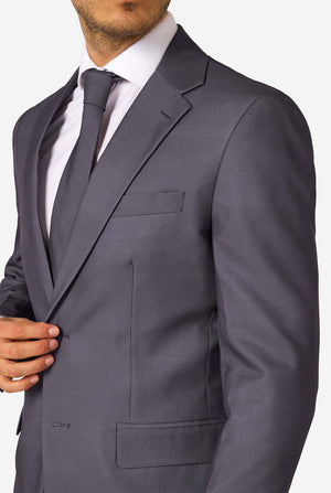 A man is wearing a stylish charcoal colored grey suit with a white dress shirt, looking confidently. Perfect formal outfit for men's special occasions, weddings, and parties. Chest close up.