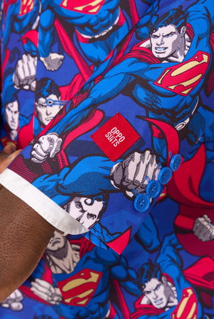 A man wearing a Superman themed suit with a red tie and a white shirt on a white background. Close up of the sleeves