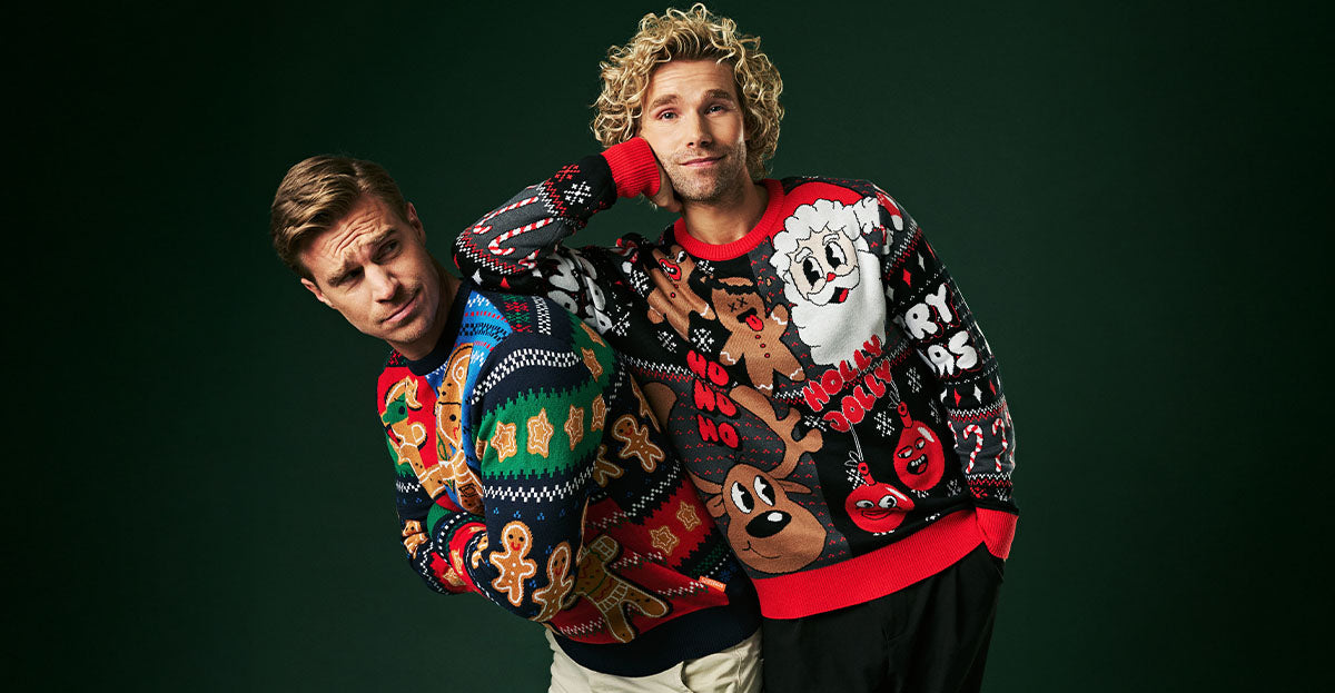 Image with dark green background and two men wearing colorful Christmas sweaters.