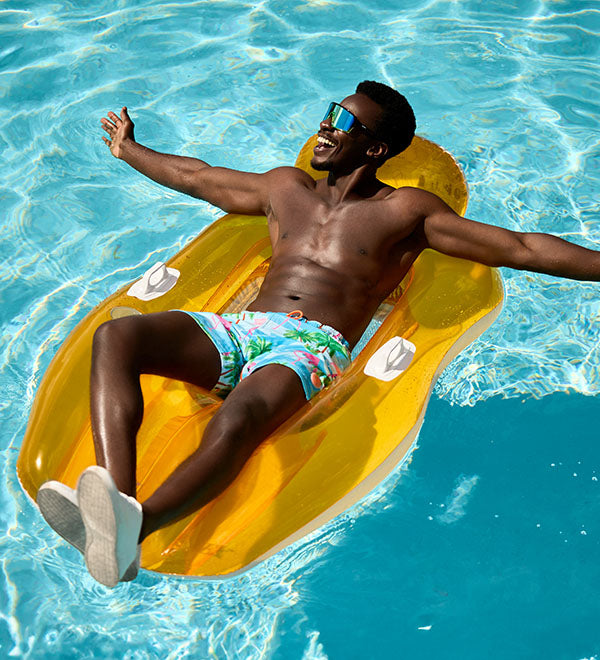 An image of a man lying on an inflatable pool floats wearing the Flaminguy swimshorts.