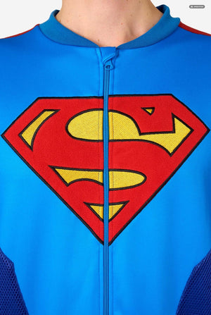 Close-up of a blue zip-front jacket with a large red and yellow Superman shield logo on the chest, shown on a person wearing it.