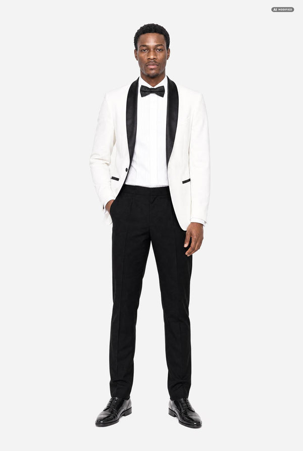 A man modeling a white tuxedo jacket with black satin lapels, paired with a white tuxedo shirt, black bow tie, black trousers, and black dress shoes, against a light gray studio background.