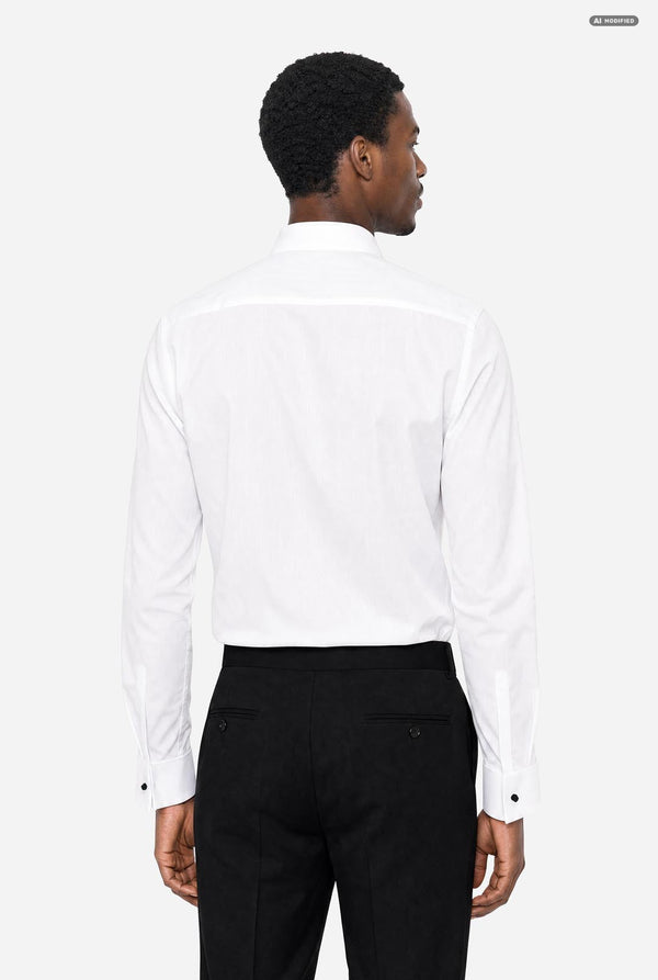 A man viewed from the back wearing a crisp white long-sleeve dress shirt and black trousers, set against a plain light gray studio background.
