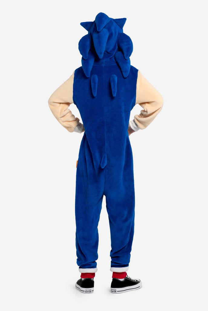 A kid is wearing a playful blue and beige Sonic the Hedgehog-themed kid onesie from OppoSuits. The cozy onesie features a zip-up front and an attached hood designed to resemble Sonic’s iconic face, complete with ears and an expressive gaze. The blue body of the suit contrasts with a beige belly, mimicking Sonic's classic look. This fun, comfortable, and stylish onesie is perfect for lounging, themed parties, or cosplay events, bringing nostalgic video game vibes to any occasion. View from the back.