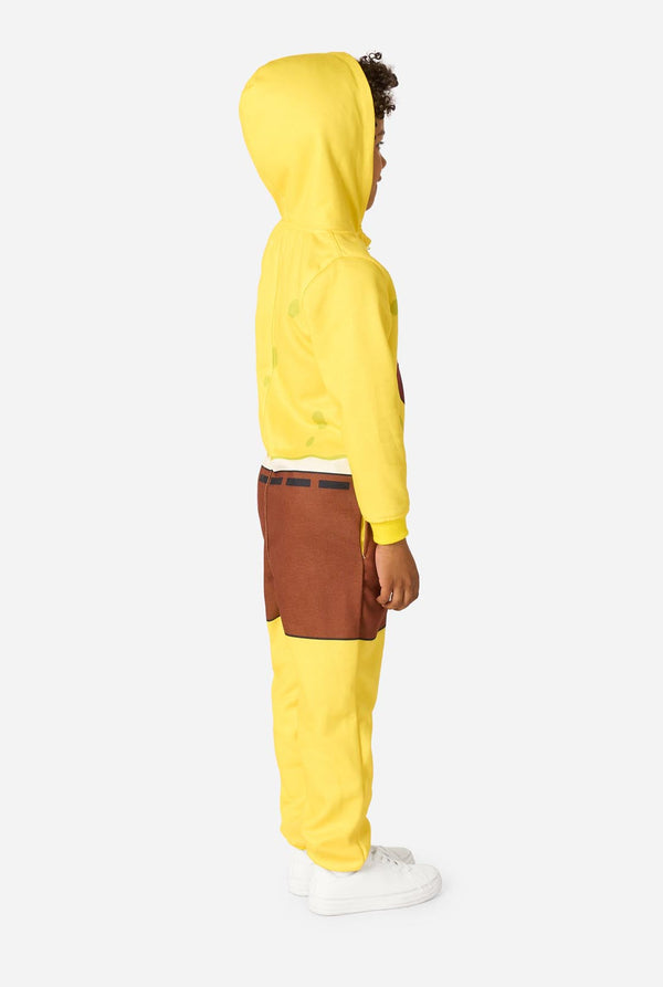 Child wearing a yellow SpongeBob onesie with a white background, image from the side full body.