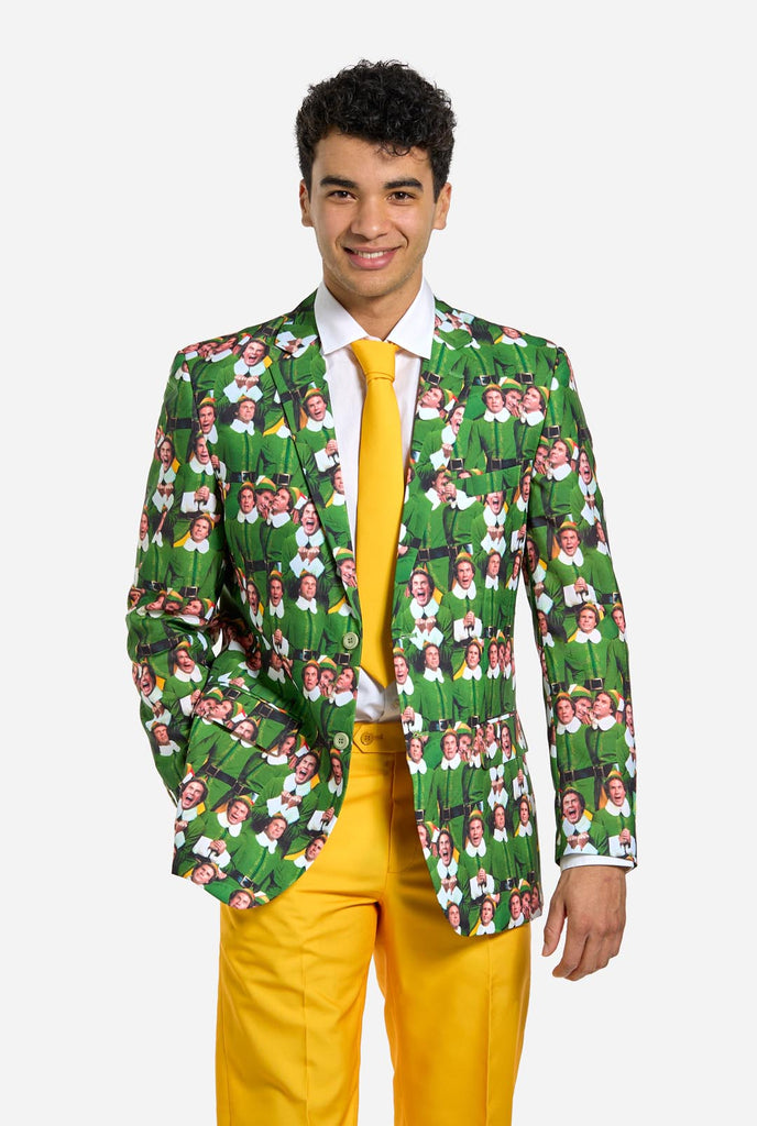 Man wearing men's Christmas suit with the character ELF on the jacket and yellow pants. Suits consists of all over print jacket with ELF Christmas movie character, yellow pants and yellow tie. Man also wearing a white shirt.