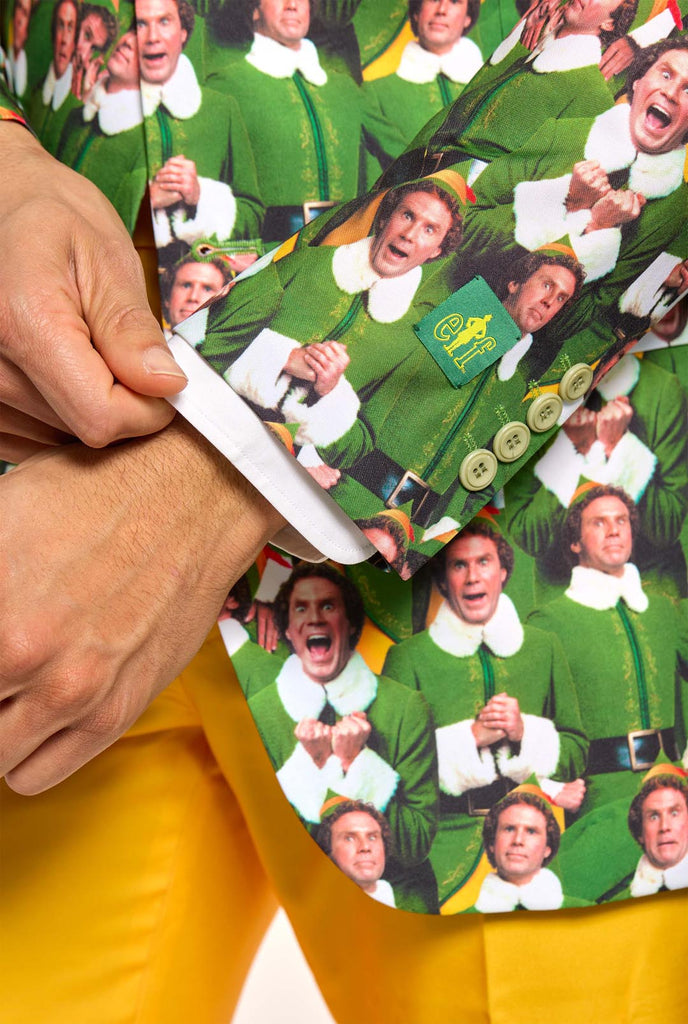 Man wearing men's Christmas suit with the character ELF on the jacket and yellow pants. Suits consists of all over print jacket with ELF Christmas movie character, yellow pants and yellow tie. Man also wearing a white shirt. Sleeve close up.