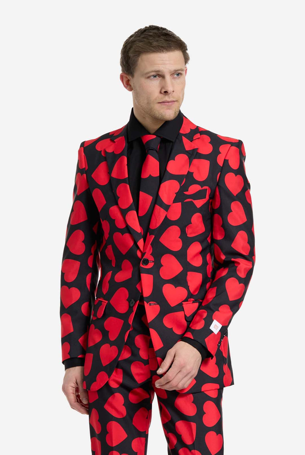 Man wearing a black suit with red heart patterns on a white background