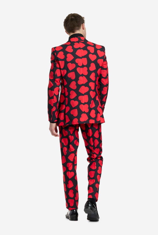 Person wearing a red and black heart-patterned suit on a white background, view from the back