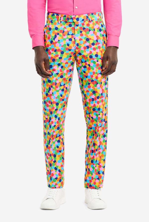 Man wearing men's suit with multicolor all-over confetti print and pink dress shirt. Suit consist of jacket, pants and tie. Pants view.