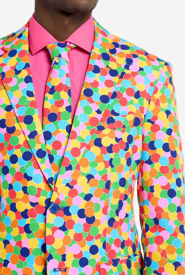 Man wearing men's suit with multicolor all-over confetti print and pink dress shirt. Suit consist of jacket, pants and tie. Chest close-up.