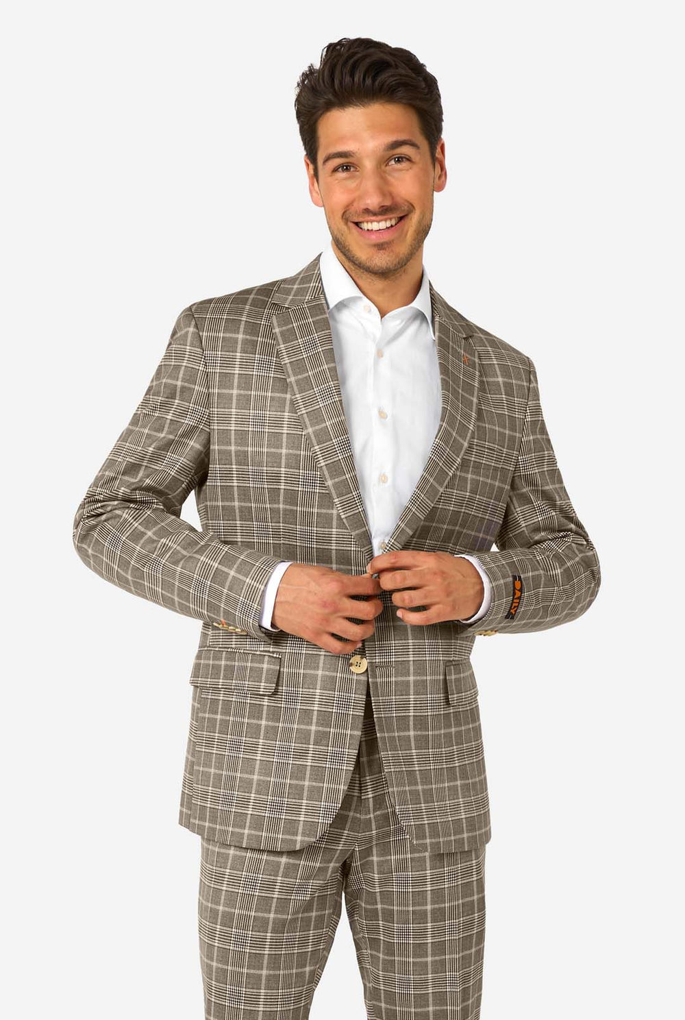 A men wearing a tan checkered suit with a white dress shirt. The suit has a modern fit with two buttons and flap pockets. He stands against a plain white background.