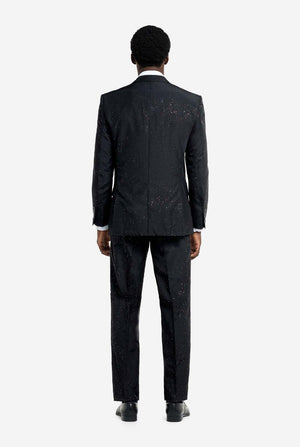 Image of a man wearing an OppoSuits Glitzy Glitter men's suit with glitters and white men's shirt. Suit consist of pants, jacket and tie. View from the back.