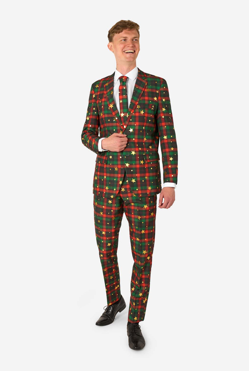 Man wearing a red and green tartan plaid suit with gold star and dot accents, standing with one hand adjusting his matching tie.