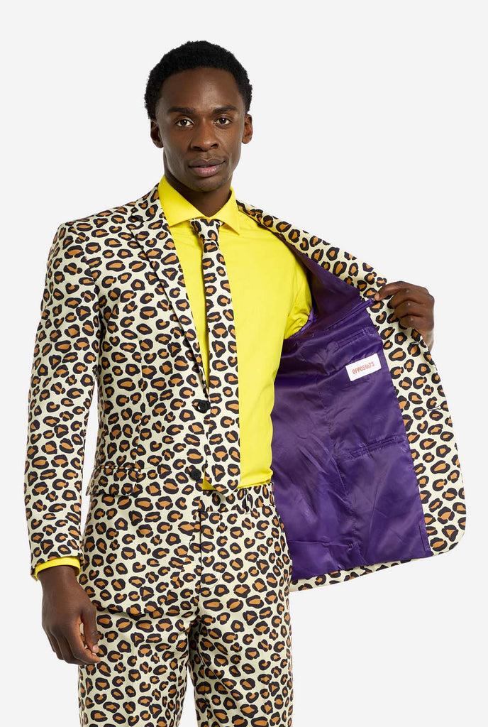 Image of a man wearing an OppoSuits The jag men's suit with panther print and yellow men's shirt. Suit consist of pants, jacket and tie. Holding one side of the jacket open.