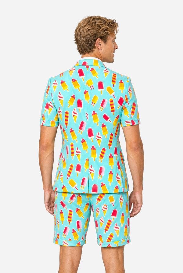 Man wearing light blue summer suit with ice cream and ice loly print. Suits consists of shorts, short sleeved blazer and tie. View from the back.