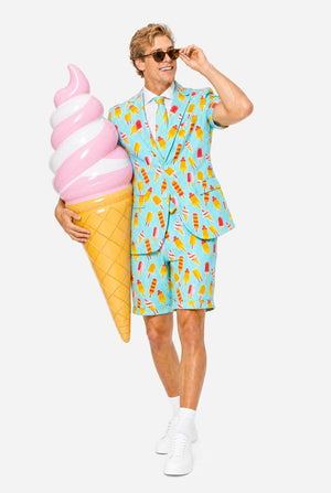 Man wearing light blue summer suit with ice cream and ice loly print. Suits consists of shorts, short sleeved blazer and tie. Holding big plastic ice cream and wearing sunglasses.