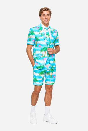 Man wearing a colorful tropical-themed suit, with palm trees and pink flamingos on a light background. Full body image.
