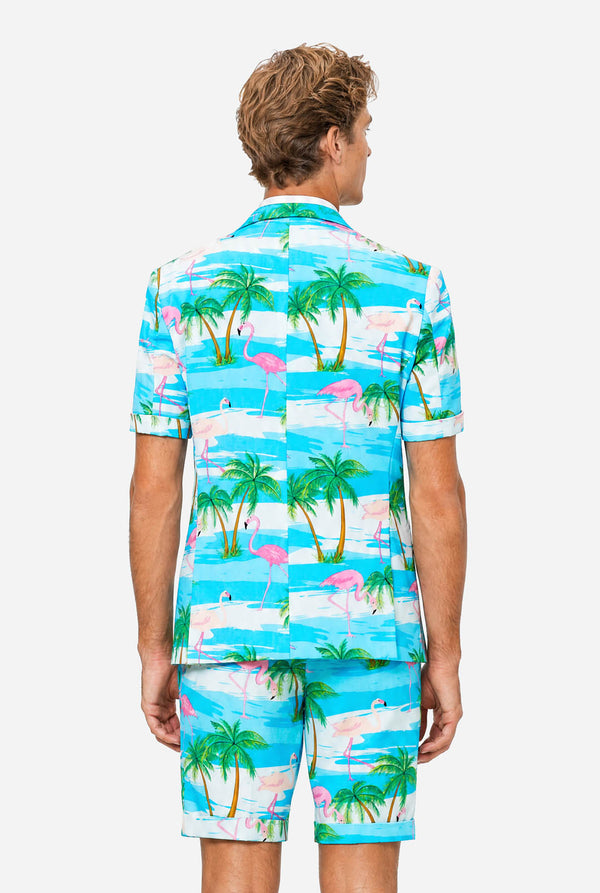 Man wearing a colorful tropical-themed suit, with palm trees and pink flamingos on a light background. View from the back.