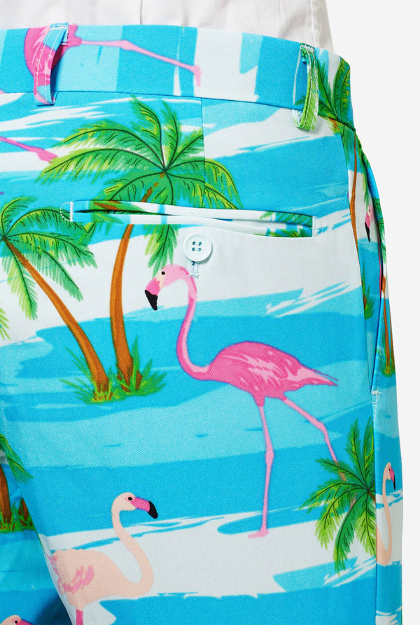 Man wearing a colorful tropical-themed Shorts, with palm trees and pink flamingos on a light background. Close up back pocket.