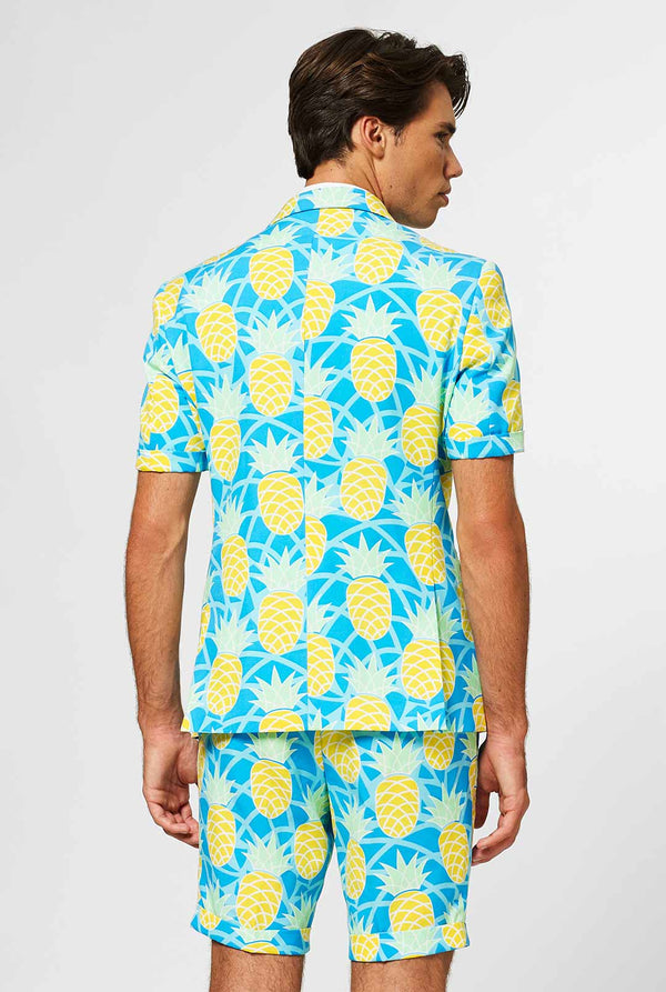 Man wearing blue summer suit with pineapple print. Back.