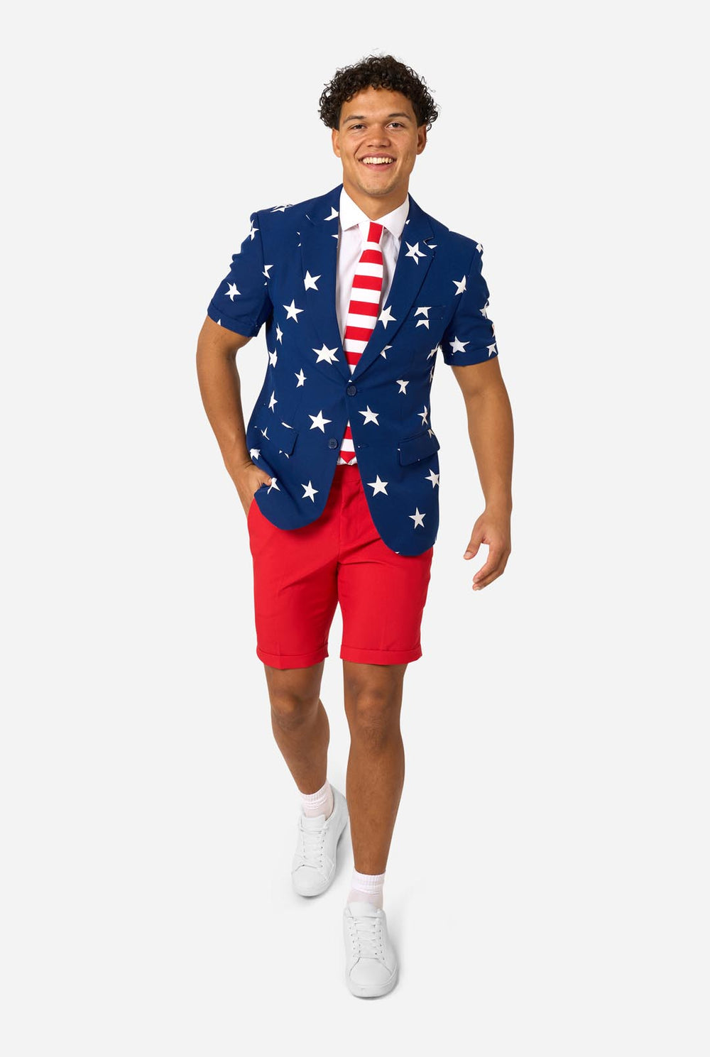 Person wearing a blue blazer with white star patterns, white shirt, and red shorts on a white background