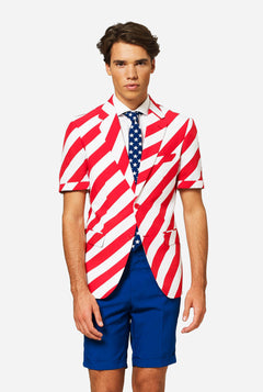 Man wearing a red, white-striped blazer and blue shorts. Resembling an American flag pattern on a plain background