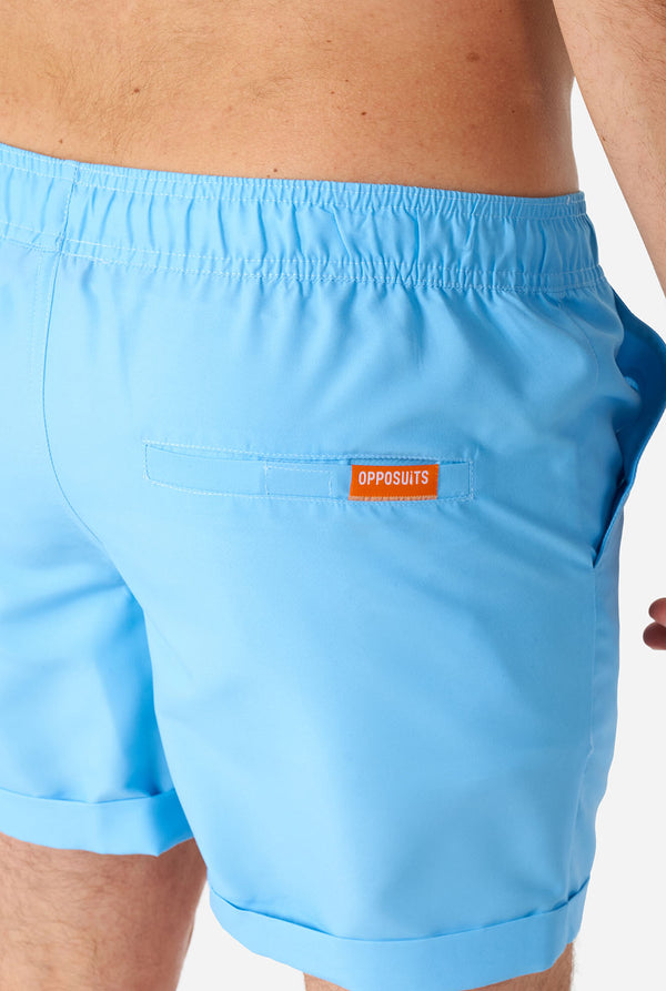 Man wearing light blue summer set, consisting of shirt and shorts. Zoomed in on shorts