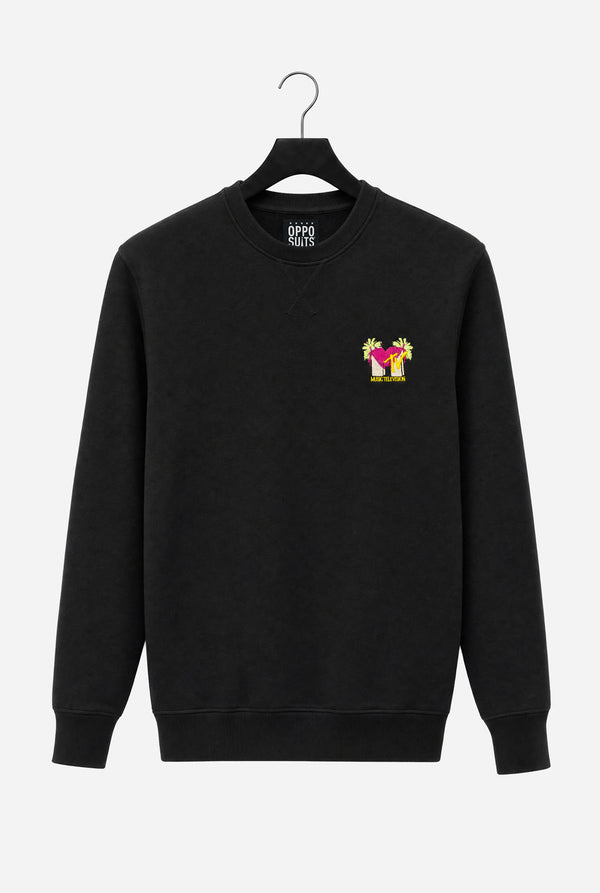 A black crewneck sweatshirt hanging on a black hanger against a light gray background, featuring a stylized MTV logo embroidery in Pink and yellow on the chest.