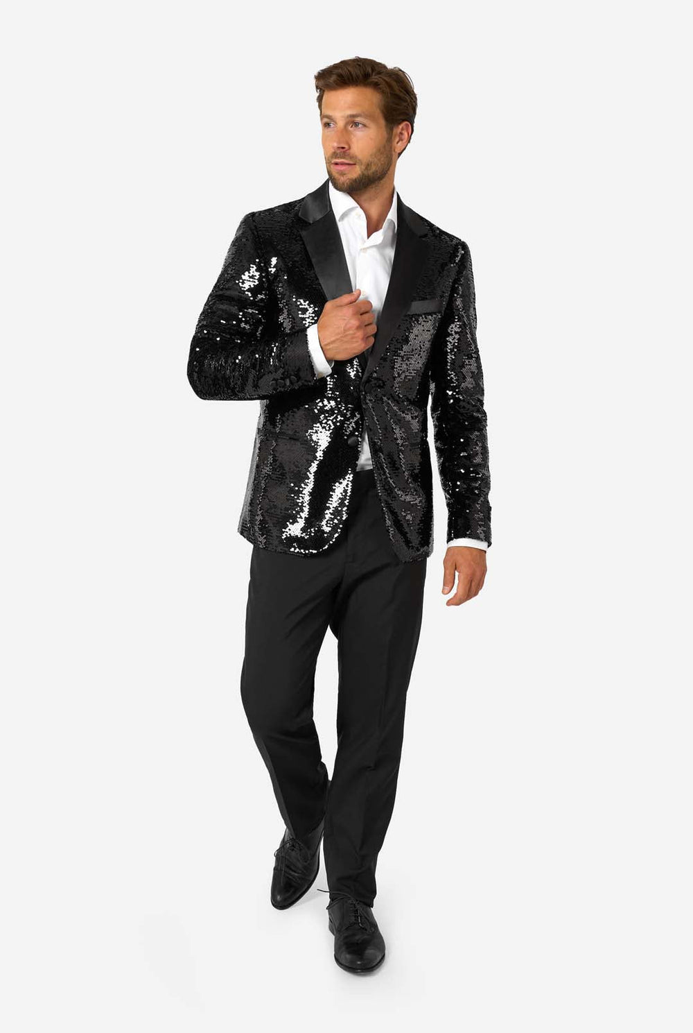 Man wearing a black sequin blazer with a satin shawl collar, paired with a white dress shirt and black trousers, standing and smiling at the camera.