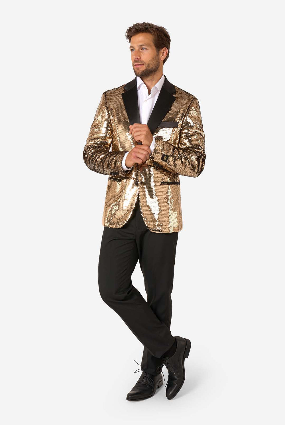 Man wearing a shiny gold sequin blazer with black satin lapels and black trousers, standing facing forward.