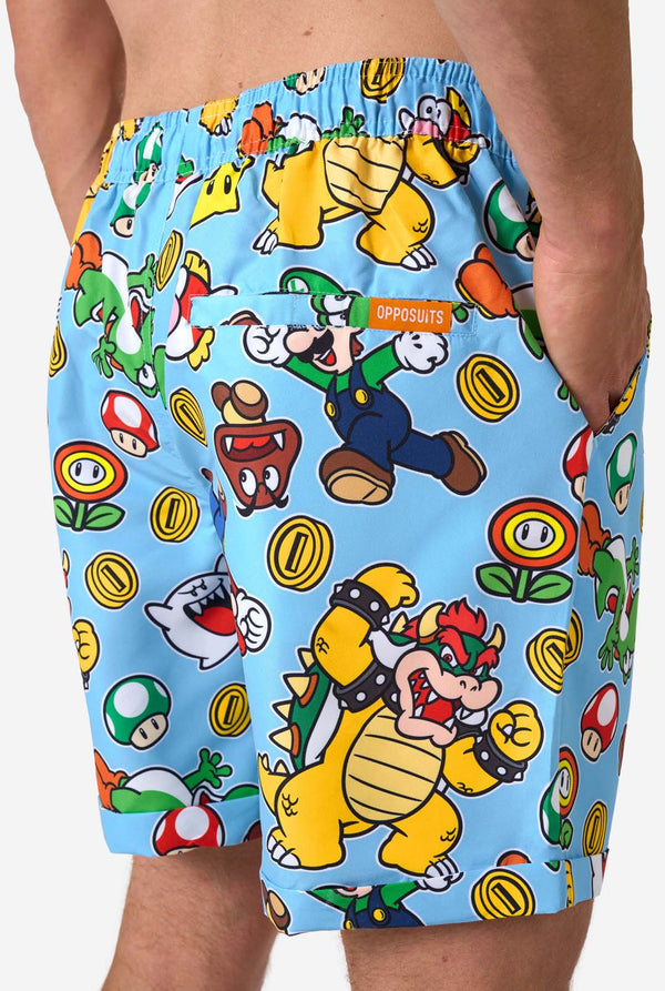 Man wearing a colorful Mario-themed shirt and shorts set on a light background. Back of shorts close-up.