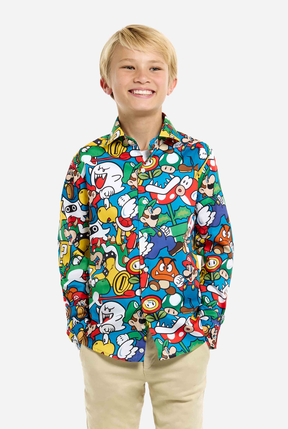 Image of teen wearing a Super Mario all over print shirt. Main color is blue, but there is also yellow, red and white. He has his hands in his pockets.