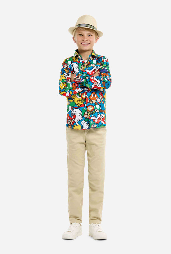 Image of teen wearing a Super Mario all over print shirt. Main color is blue, but there is also yellow, red and white. Full body image with kid wearing hat.