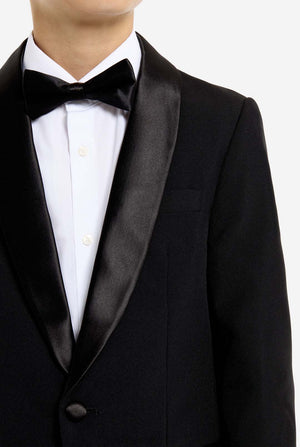 Black tuxedo with white shirt and bow tie on a plain background