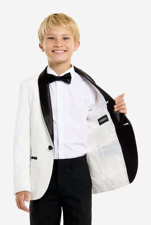 Young boy wearing a white tuxedo with black bow tie and pants on a white background